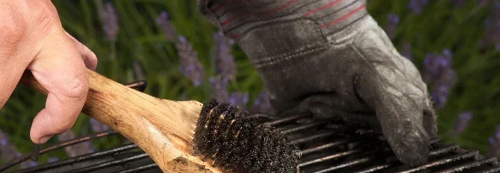 Person reinigt Grillrost mit Bürste